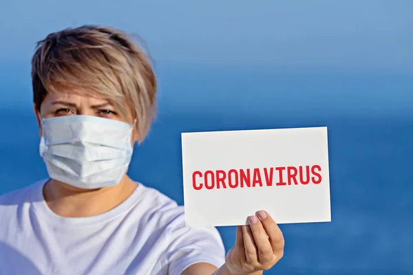 Cerrahi maskeli kadın, Coronavirus 2019 metni ile boş duruyor.