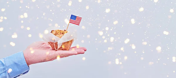 Cupcake with American flag on male palm against light background — Stock Photo, Image