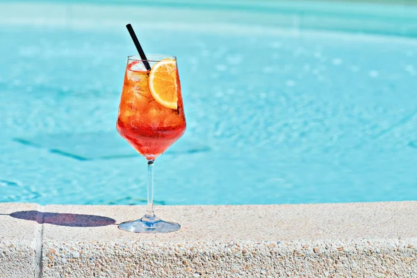 Havuz kenarındaki turkuaz suya karşı bir bardak soğuk Aperol spreyi. Geleneksel İtalyan Yazı Aperitif Kokteyl Konsepti