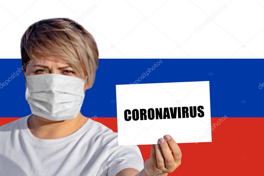 Woman in face mask hold sheet with inscription CORONAVIRUS against Russian flag. Concept of attention about spread of Chinese Coronavirus COVID-19 Novel Pneumonia virus