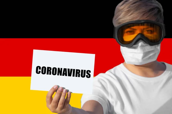 戴着面具和护目镜的女人拿着印有 Coronavirus 字样的床单对抗德国国旗 中国高粱Covid 19新型肺炎病毒在全球传播的关注概念 — 图库照片