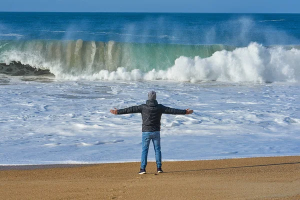 Vista trasera del hombre disfrutando de una gran ola de océano en una playa de arena vacía —  Fotos de Stock