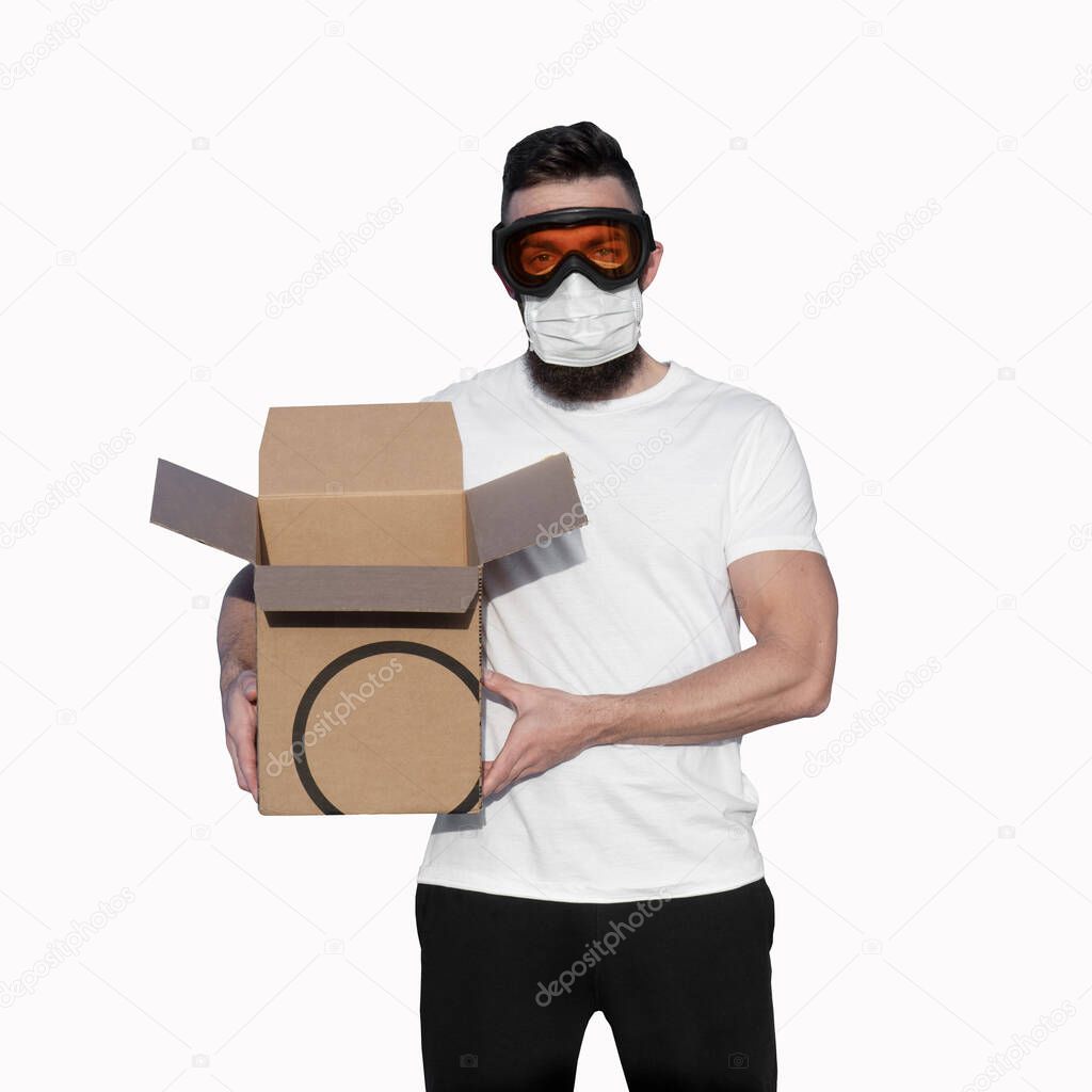 Man wearing protective glasses and face mask unpacking cardboard box on white background. Contactless delivery during pandemic of coronavirus Covid-19 concept