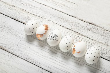 Beyaz ahşap zemin üzerinde paskalya yumurtaları, yazı için yer, üst görünüm