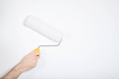 Adam elinde bir silindir tutuyor. Beyaz duvar, onarım. Yapıcı