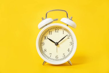 Sarı arka planda beyaz alarm saati.