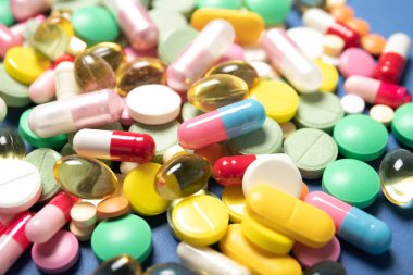 Mavi arka planda haplar ve kapsüller, yakın plan. Tıp ve sağlık kavramı