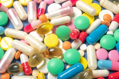 Mavi arka planda haplar ve kapsüller, yakın plan. Tıp ve sağlık kavramı