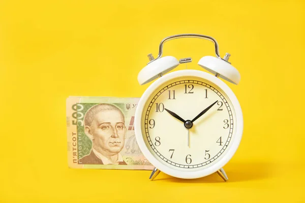Sarı arka planda beyaz çalar saat ve para. Ukrayna Hryvnia 'sı. Mali işler. Kredi.