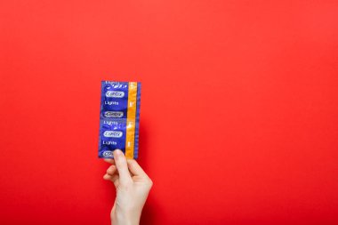 Kız prezervatif tutuyor Contex. Mesaj için kırmızı arkaplan yeri. Kiev, Ukrayna