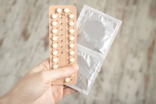 The girl holds contraceptive pills and condoms in her hands. Contraception