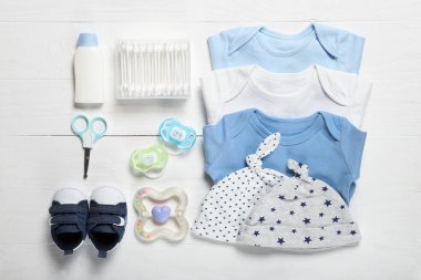Tahta arka planda bebek kıyafetleri ve aksesuarları olan düz kompozisyon.