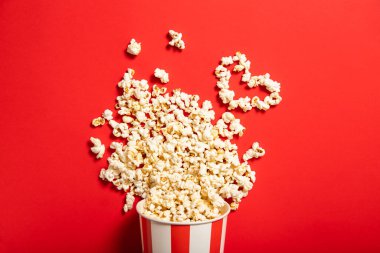 Kırmızı zemin üzerinde patlamış mısır olan kağıt bardak.