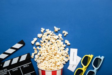 Mavi arka planda patlamış mısır ve film alkışı olan kağıt bardak, metin için yer