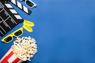 Mavi arka planda patlamış mısır ve film alkışı olan kağıt bardak, metin için yer