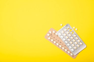 Sarı arka planda kadın oral doğum kontrol hapı kabarcığı..