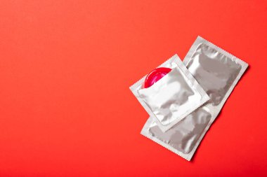 Kırmızı arka planda renkli prezervatif. Metin için yer, üst görünüm. İlaç ve sağlık hizmetleri