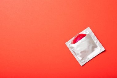 Kırmızı arka planda renkli prezervatif. Metin için yer, üst görünüm. İlaç ve sağlık hizmetleri
