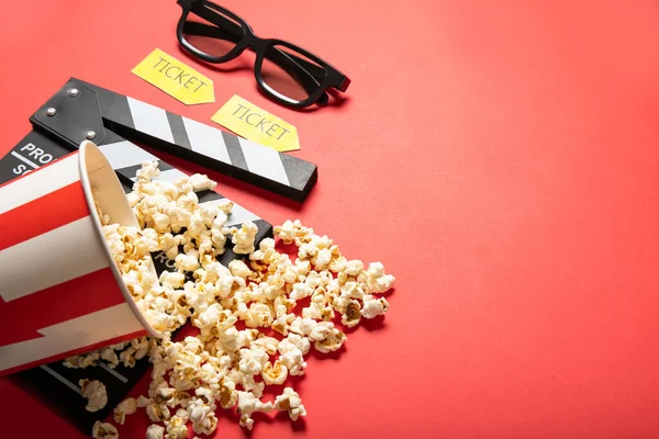 Paper cup with popcorn and movie clapper board on a red background. Place for text