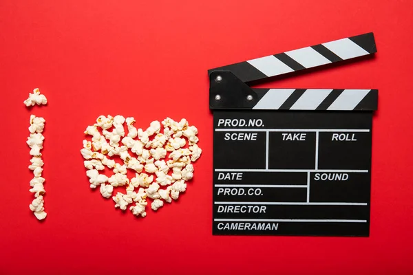 Plate with popcorn and movie clapper board on a red background