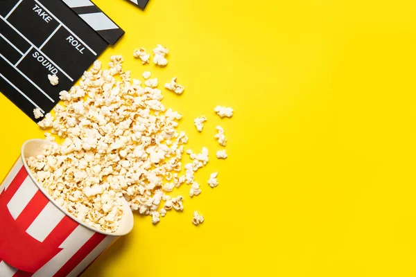 Sarı arka planda patlamış mısır ve film alkışları olan kağıt bardak, metin için yer