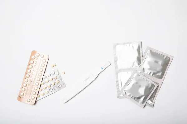 Condoms, birth control pills and pregnancy test on a white background