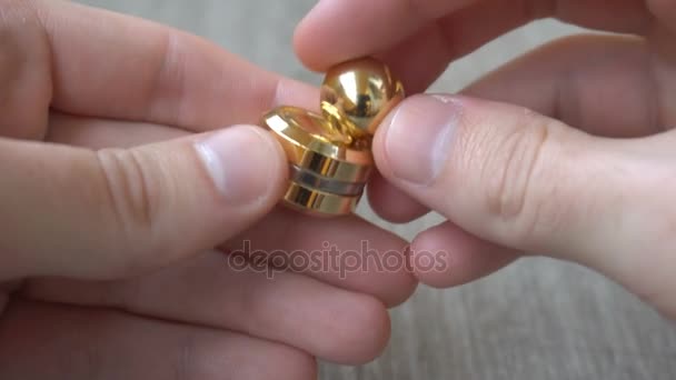 New gold fidget Orbiter,spinning in the hand of a young man on gray background — Stock Video