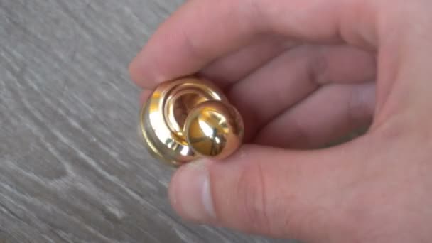 Nieuwe goud fidget Orbiter, spinnen in de hand van een jongeman op een grijze achtergrond — Stockvideo