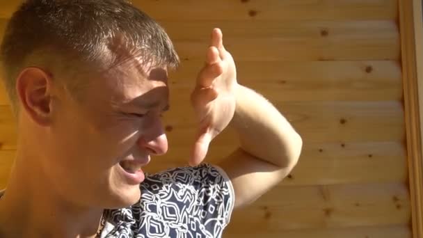Portrét mladého muže, koukal a pokrývající jejich tvář rukou proti záření slunce — Stock video