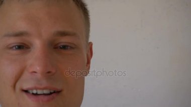 Gülümsemek gülümseyen genç adamın beyaz arka plan üzerinde izole kamera bakıyor. Yüz ifadeleri değiştirir sakallı bir adam portresi. Kameraya bakarak t-shirt ile gurur ve memnun adam