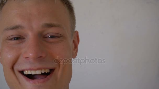Gros plan d'un jeune homme souriant regardant une caméra isolée sur fond blanc. Portrait d'un type barbu qui change d'expression faciale. Homme fier et satisfait avec t-shirt regardant la caméra — Video