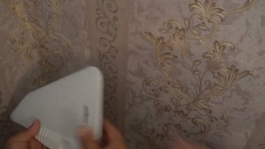 Duvardaki bir spatula sıkma ile duvar kağıdı yumuşatmak için çalışan el duvar kağıdı yapıştırma işlemi