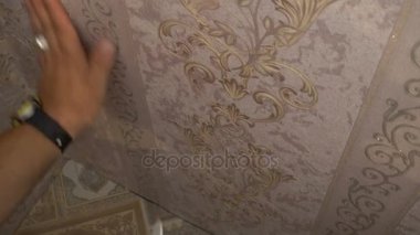 Duvardaki bir spatula sıkma ile duvar kağıdı yumuşatmak için çalışan el duvar kağıdı yapıştırma işlemi