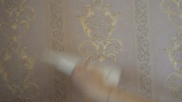 Процесс склеивания обоев на стене, рука рабочего, чтобы сгладить обои с помощью зажима лопатки — стоковое видео