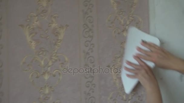 Processen med limning Wallpaper på væggen, hånden af arbejdstageren til at glatte Wallpaper med en spatel fastspænding – Stock-video