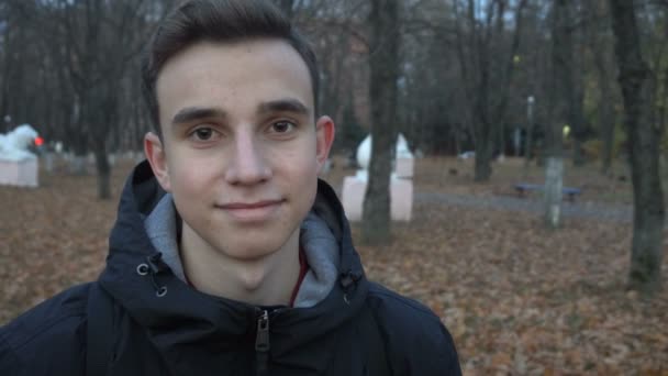 Retrato de un joven sonriente de pie en otoño Park — Vídeo de stock