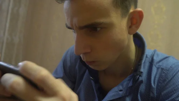 Innoissaan nuori mies pelaa kiehtova peli älypuhelimeen — kuvapankkivalokuva