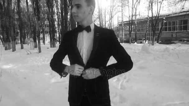 Giovane uomo in posa in smoking in inverno contro la neve bianca, girato in stile retrò — Video Stock