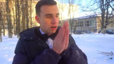 genç bir adam kışın, karda duran sıcak tutmaya çalışıyor