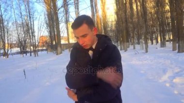 genç bir adam kışın, karda duran sıcak tutmaya çalışıyor