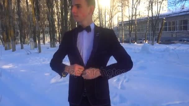 Mladý muž pózuje v smokingu v zimě na bílém sněhu, zastřelil v retro stylu — Stock video