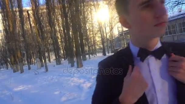 Joven posando en un esmoquin en invierno contra la nieve blanca, rodado en estilo retro — Vídeos de Stock