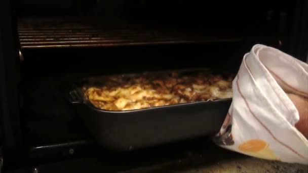 Ein Mann zieht Backkartoffeln mit Fleisch aus dem Ofen — Stockvideo