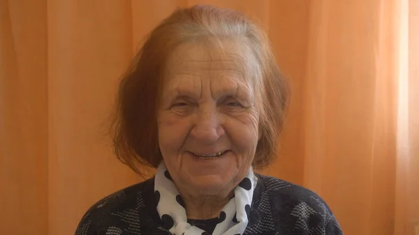 Porträtt av en leende äldre kvinna tittar på kameran — Stockfoto
