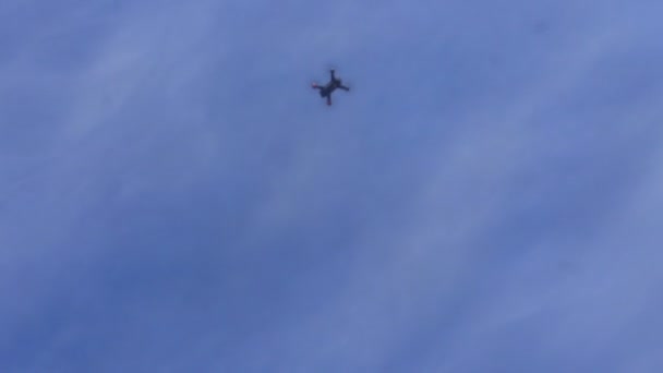 Квадрокоптер взмывает в голубое небо, стреляя снизу — стоковое видео