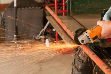 Duş boru, bir bölümünü kesmek için kesme bir bıçak kıyma makinesi kullanan bir adam closeup atölye arasında kıvılcım