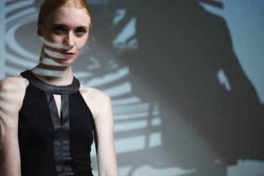 Vücudunda gölgesi olan zarif çıplak bir kadının moda sanat stüdyosu portresi.