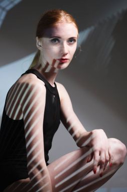 Vücudunda gölgesi olan zarif çıplak bir kadının moda sanat stüdyosu portresi.