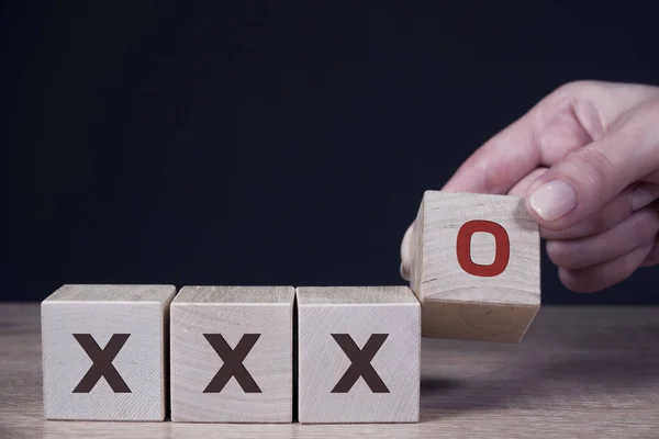 Maschio mano mettere O schermo di stampa simbolo su cubo di legno e X di legno — Foto Stock