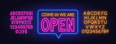 Girin, tuğla duvarda açık neon tabela var..